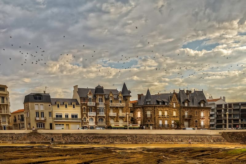 Architecture Belle Époque en bord de mer en Vendée - Façades historiques sous un ciel dramatique avec vol d'oiseaux